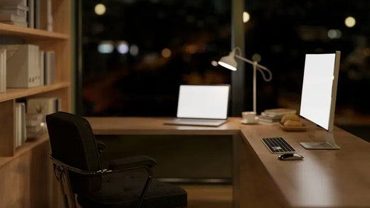 An wooden l-shaped office desk by the window at night